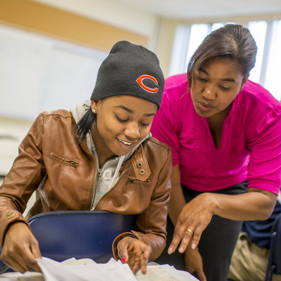 A professor points something out to a student in the Spanish textbook.